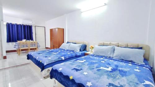 a bedroom with two beds with blue covers and a table at Apartment near Central Festival Hatyai in Hat Yai