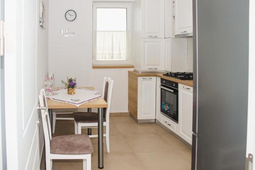 a kitchen with white cabinets and a table with chairs at Apartament Rubin in Sibiu