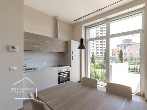 a kitchen with a wooden table and a large window at Open Space - Garden & Jacuzzi - Self Check-in in Milan