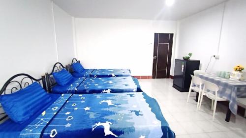 a bedroom with two beds with blue sheets and a table at Apartment near Central Festival Hatyai in Hat Yai