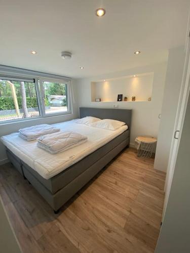 a bedroom with a bed and a large window at Luxe groot chalet voor 6 personen op de Veluwe! in Doornspijk