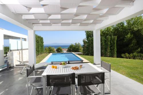 a patio with a table and chairs and a swimming pool at Villa Paradisio - Pool, Sea View, 4bdrms,BBQ in Hanioti