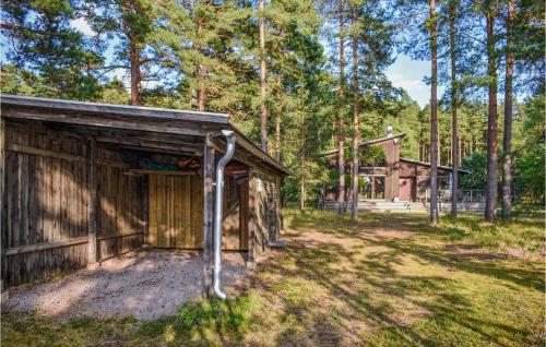 a wooden shed in the woods with a house in the background at Gorgeous Home In Färjestaden With Wifi in Färjestaden