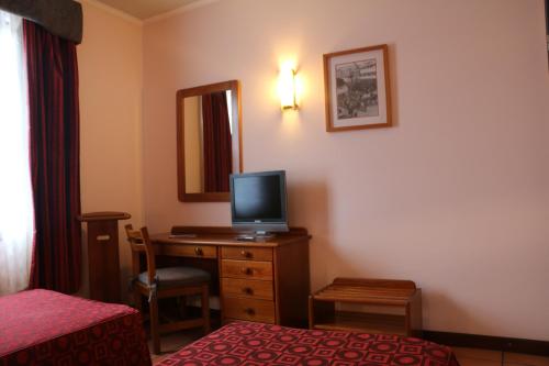 a hotel room with a bed and a desk with a television at Apartamentos Turisticos Verdemar in Horta