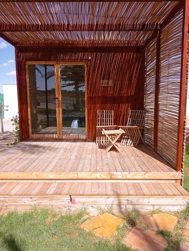 a wooden cabin with a bench on a deck at Garden12 Outdoor & More in Douz
