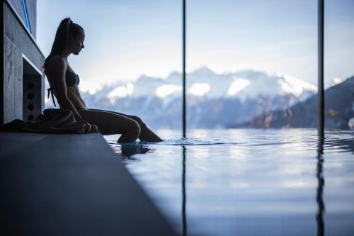 a woman sitting on the edge of a swimming pool at DAS GERSTL Alpine Retreat in Malles Venosta