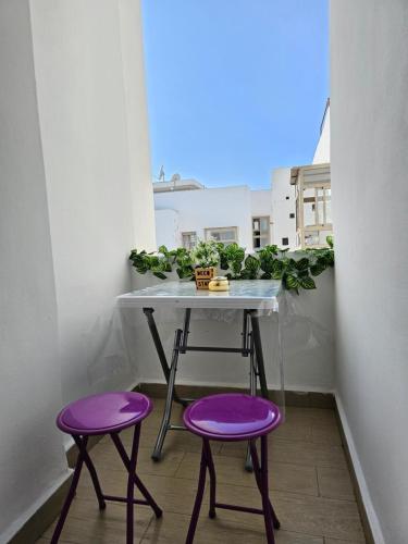 a table and two purple stools on a balcony at MIA Appartement N2 - Élégance, Confort et Sérénité in Casablanca