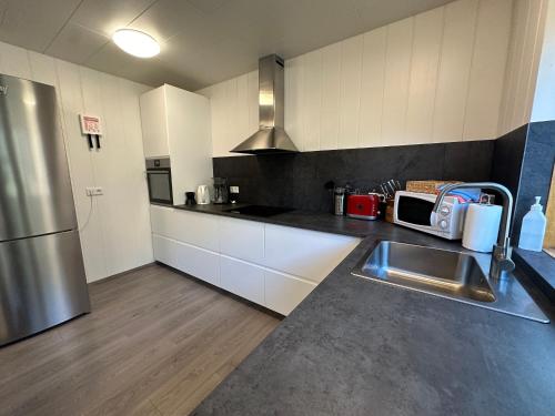 a kitchen with white cabinets and a stainless steel refrigerator at Lodge Borgarbrekka in Lón South East of Iceland - Birta Rentals in Höfn