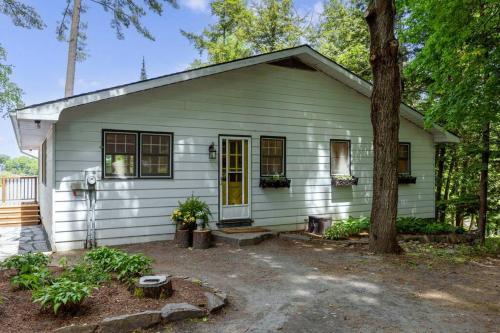 a green house with a tree in front of it at 4Bdrm Muskoka Retreat, Fire Table, Games, Netflix in Port Carling