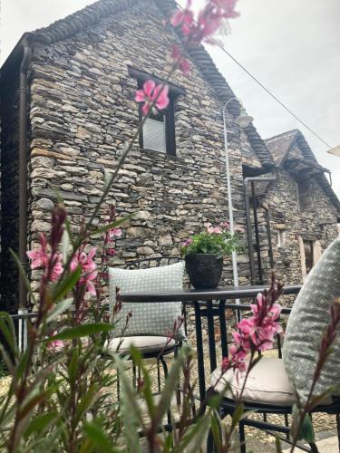 a stone house with two chairs and a window at Rustico Lucy in Gordola