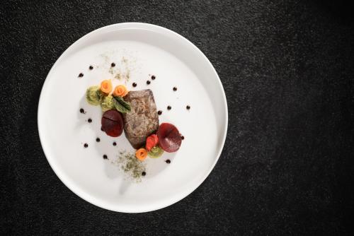 a white plate with food on a black table at DAS GERSTL Alpine Retreat in Malles Venosta