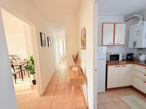 une cuisine avec des placards blancs et un couloir avec une table dans l'établissement Bastia vue Mer et Montagne, à Bastia