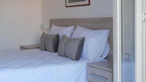 a bed with white pillows and gray pillows at B&B Bella Peschici in Peschici
