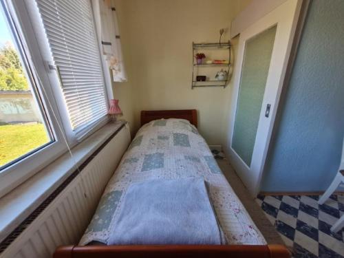 a small bed in a room with a window at Ferienwohnung Erzgebirgsblick in Bernsbach