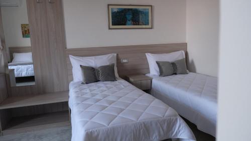 two beds in a hotel room with white sheets at B&B Bella Peschici in Peschici