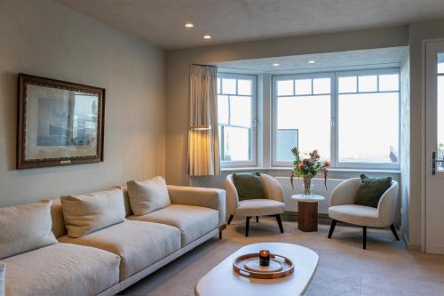a living room with a couch and chairs and windows at Unieke villa Catherine met frontaal zeezicht, parking sauna en strandcabine in De Panne