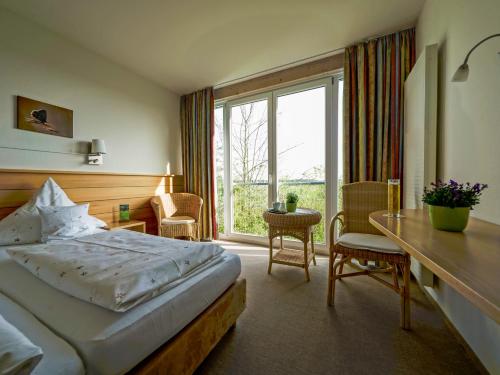 a bedroom with a bed and a desk and a window at Landgasthof/Hotel Hirsch im Grünen in Mehrstetten