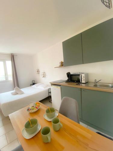 Cette chambre dispose d'une cuisine et d'une table avec des tasses. dans l'établissement Le Skate Beach studio proche plage, à Calais