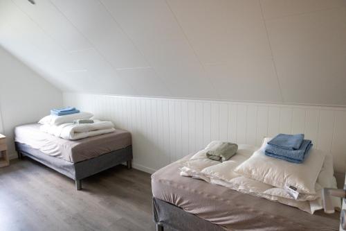 two beds in a room with white walls at Gammelbanken Seaview Suites - Modern Apartments with Sea View, Lofoten in Ballstad