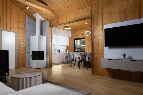 a kitchen and living room with a large tv on the wall at Chalet VLOčKA - Chalet Snowflake in Telgárt
