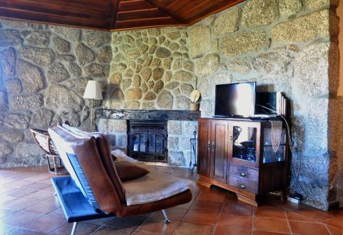 a stone walled room with a chair and a television at Casa de Fora in Fafe