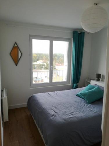 une chambre avec un lit et une grande fenêtre dans l'établissement T2bis, petit coin de paradis face à la mer, à Saint-Jean-de-Monts