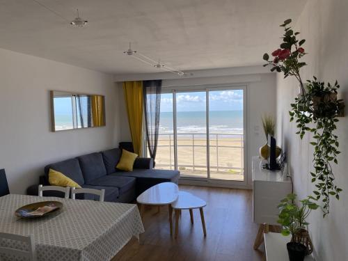 un salon avec un canapé bleu et une table dans l'établissement T2bis, petit coin de paradis face à la mer, à Saint-Jean-de-Monts