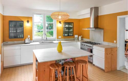 une cuisine avec des murs orange et un îlot de cuisine avec des tabourets dans l'établissement 4 Bedroom Nice Home In Étretat, à Étretat