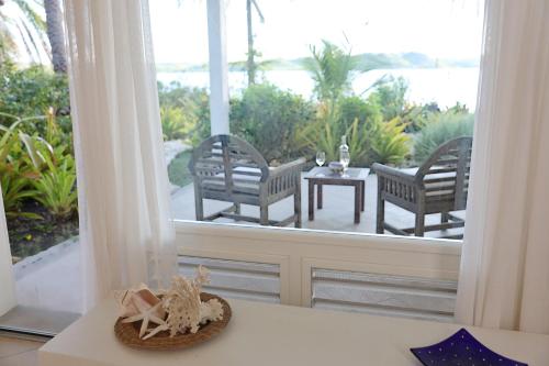 a porch with two chairs and a table and a window at East End Antigua Boutique Hotel in Willikies
