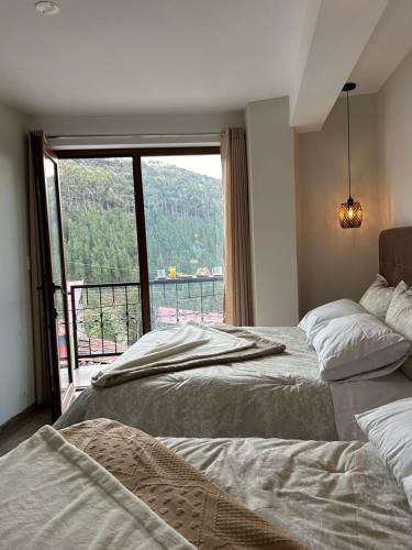 two beds in a room with a large window at Juan Placido Hospedaje in Cusco