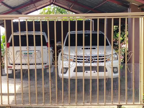 two white cars parked behind a fence at Hermosa vista, casa en Boquete. in Boquete