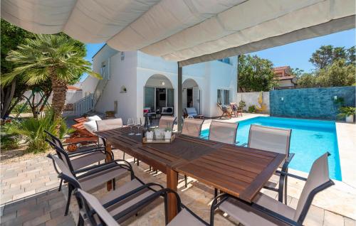 un patio con mesa de madera y sillas junto a una piscina en Beautiful Home In Vrsi Mulo With Sauna, en Vrsi