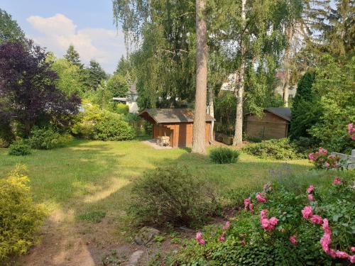un jardin avec une cabane en arrière-plan dans l'établissement Martha - Ferienhaus, 3 Schlafzimmer, 2 bis 6 Personen, S-Bahn nach Berlin, Strausseenähe, ruhige Lage, à Strausberg