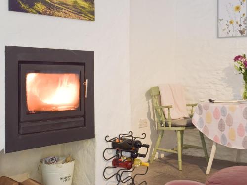 a living room with a fireplace and a chair at Y Stabl - Uk35032 in Carmarthen