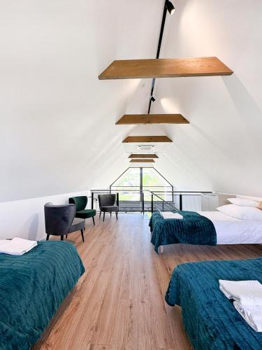 a room with two beds and chairs and a chandelier at Domy pod Borczyną in Zwierzyniec