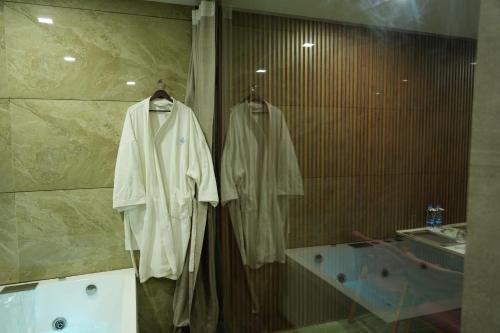 a bathroom with a robe hanging on a wall at SKD RESORT AND CLUB in Barvāla
