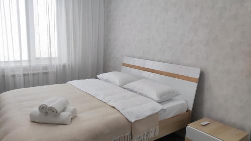 a white bedroom with a bed with a towel on it at Князя Володимира 3 CityRooms in Bila Tserkva
