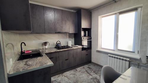 a kitchen with wooden cabinets and a sink and a window at Князя Володимира 3 CityRooms in Bila Tserkva