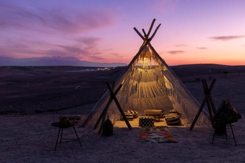 a lit up tent in the desert at sunset at Alkamar Camp Agafay in El Karia