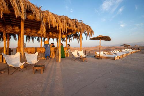 a group of people standing under a thatched roof at Alkamar Camp Agafay in El Karia