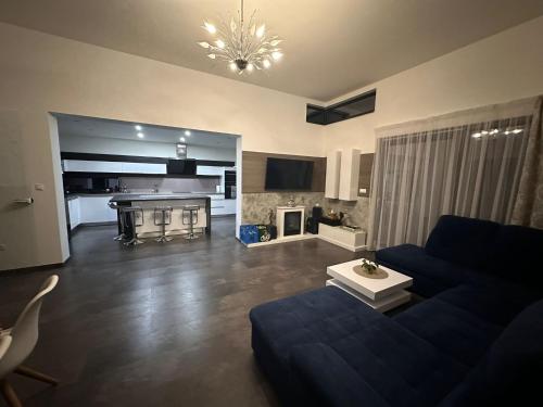 Una sala de estar con un sofá azul y una cocina. en Villa Kulacs, en Veľký Meder