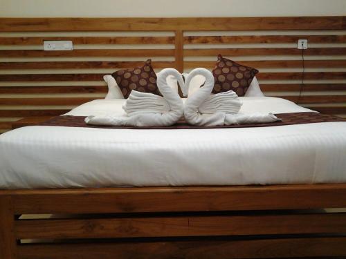 two swans shaped like hearts are sitting on a bed at Mizzle Resort in Padinjarathara
