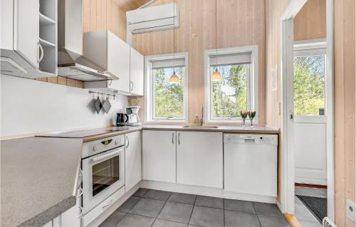 a large kitchen with white cabinets and windows at Holiday Home Frankelund Tranekær Ii in Hou