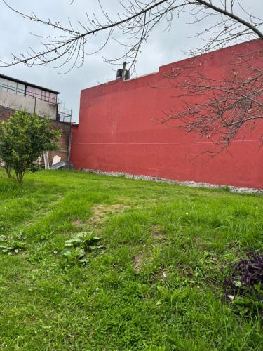 a red wall next to a field of grass at Rincón del Ángel in Zacatlán