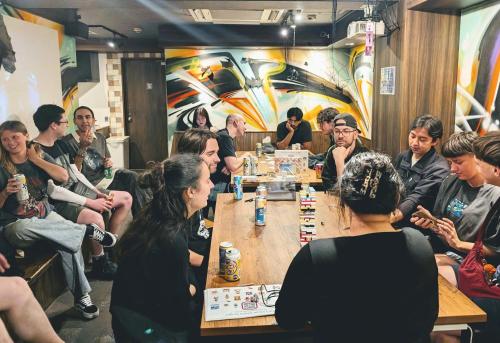 a group of people sitting around a table playing chess at R Hostel Namba south in Osaka