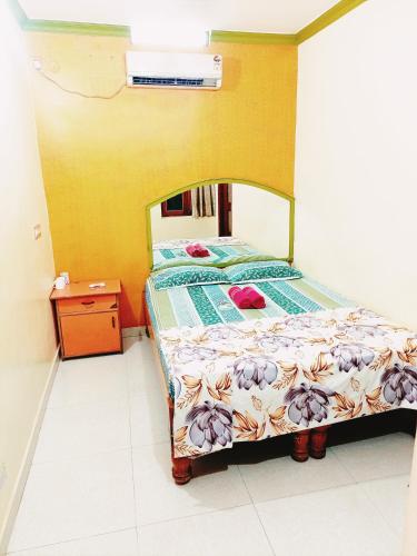 a bed in a room with a yellow wall at Thilak Home Stay in Hampi