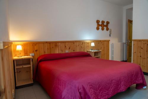 a bedroom with a red bed and two night stands at Camere vecchio borgo in Bormio