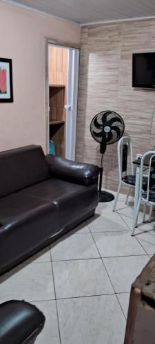 a living room with a black leather couch and a table at Casa com piscina e churrasqueira em Iguaba grande in Iguaba Grande
