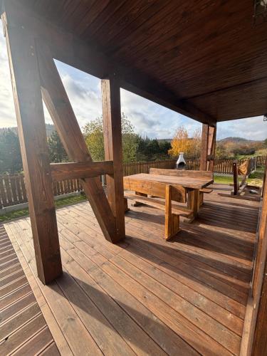 a wooden porch with a picnic table on a deck at Hereczówka 2 in Bardo