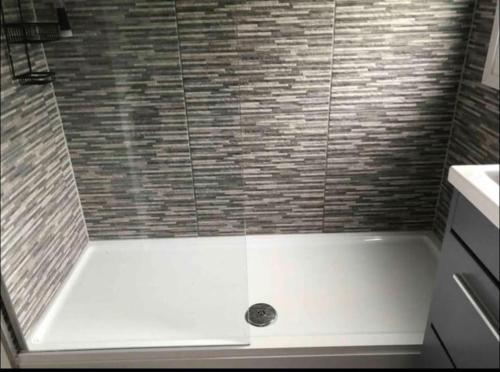 a bathroom with a shower with a white tub at Coombe Corner Cornwall in Bude